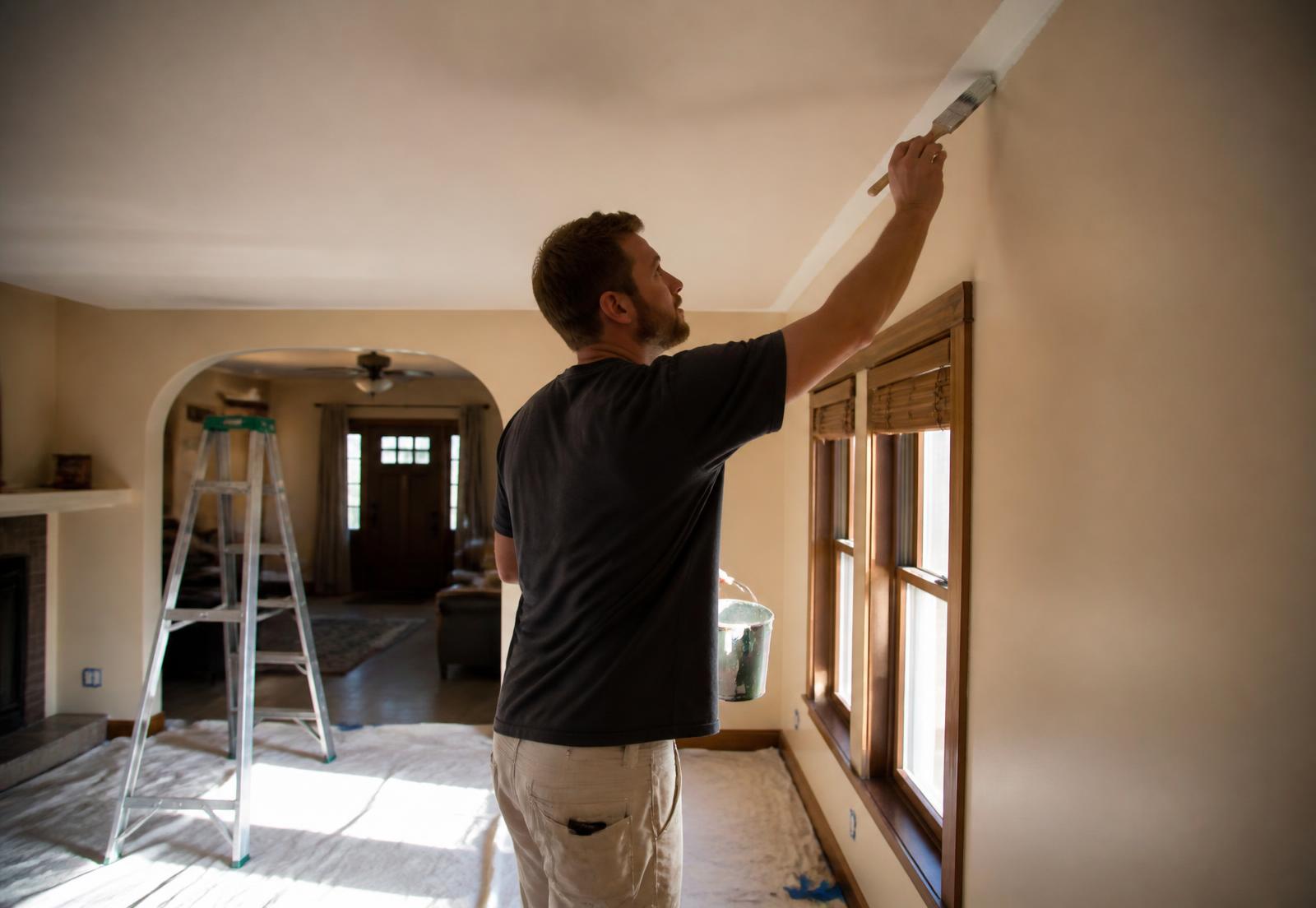 Painter cutting in a clean line along interior trim in a bright room